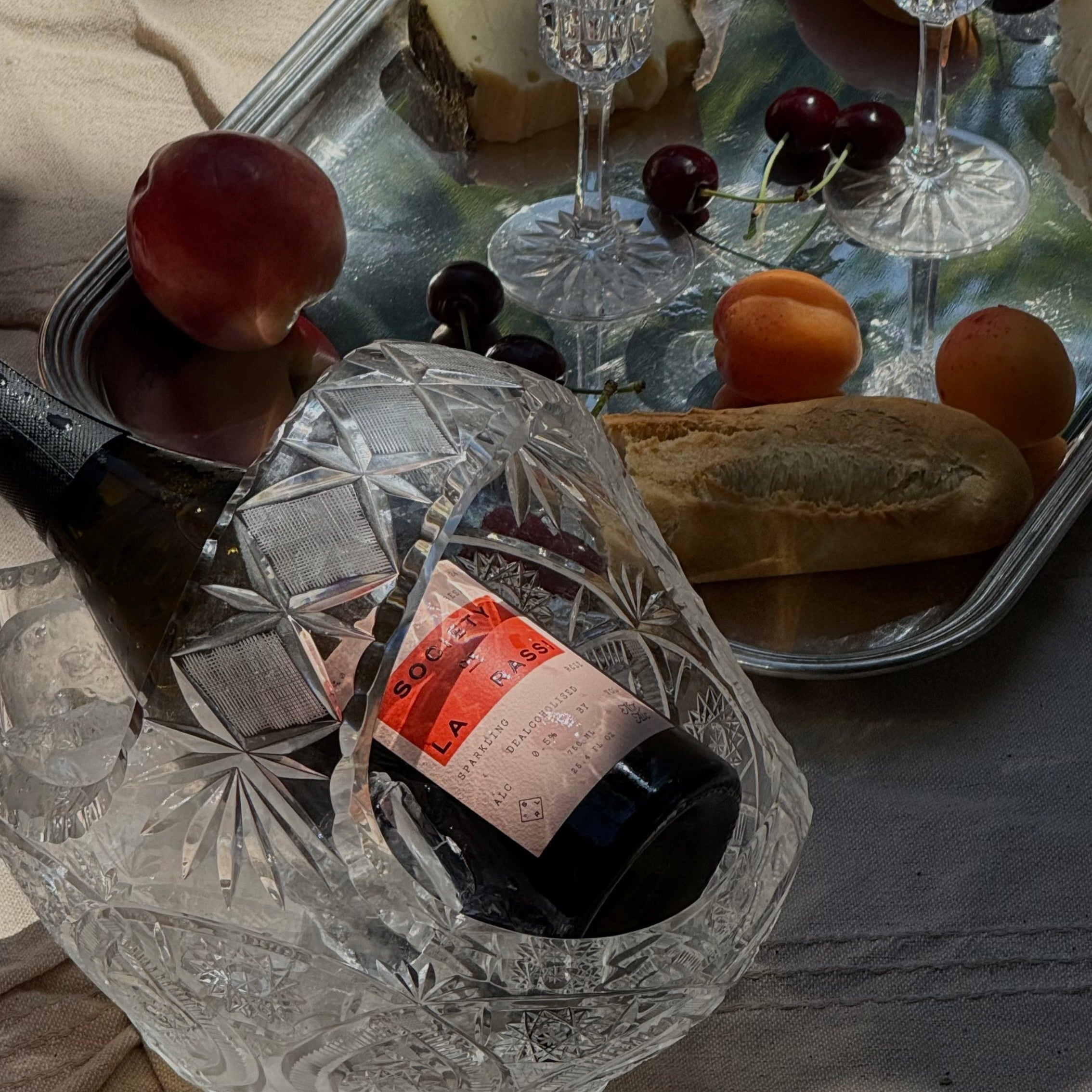 Silver tray with wine glasses, cheese, fruit and rose bottle chilling.
