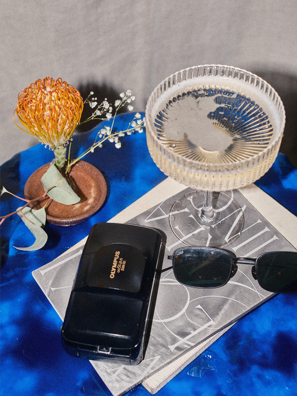 La Rassi na wine fizzing in a glass next to a vintage digital camera and pair of sunglasses.