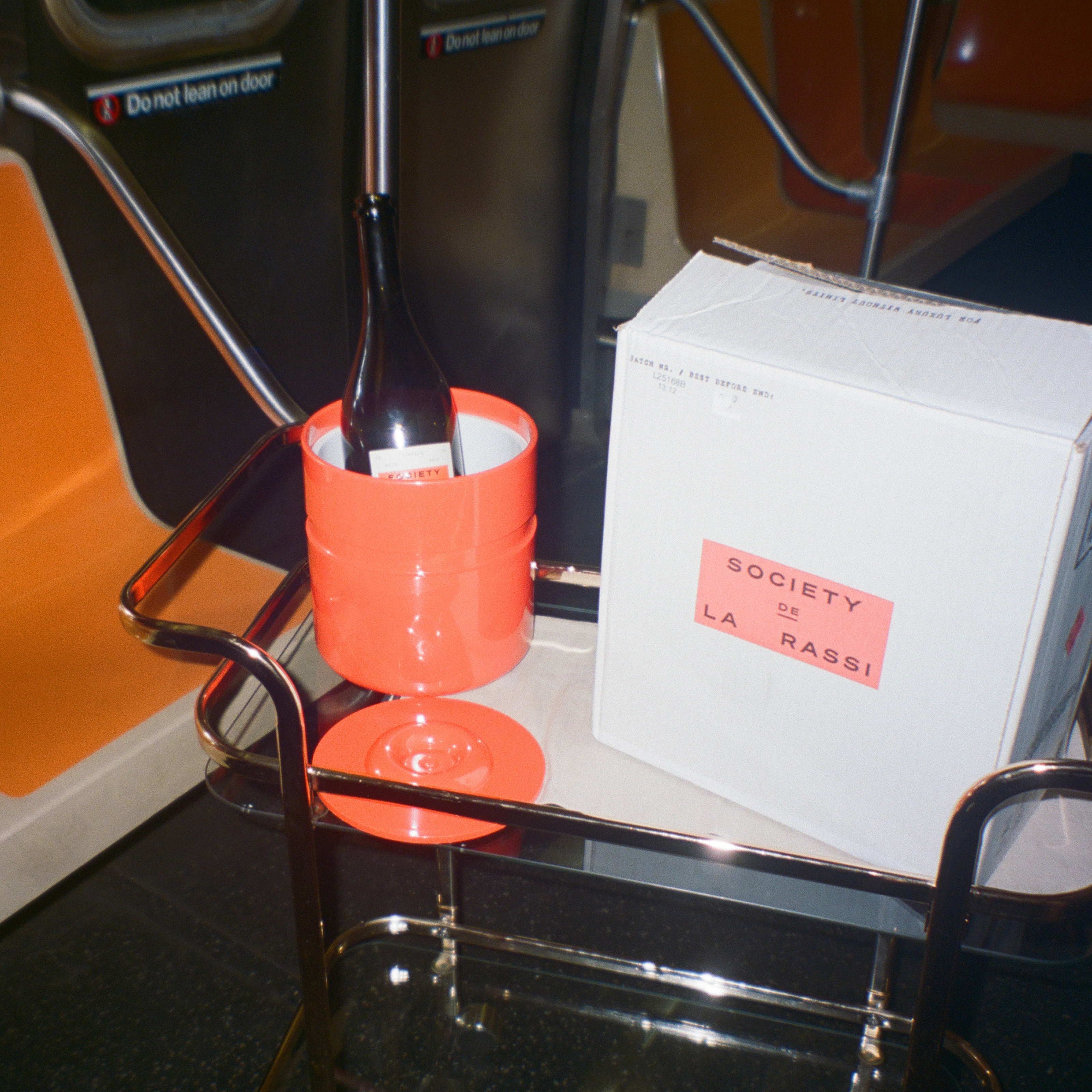 Bottle in a retro ice bucket on a bar cart with a box of wine