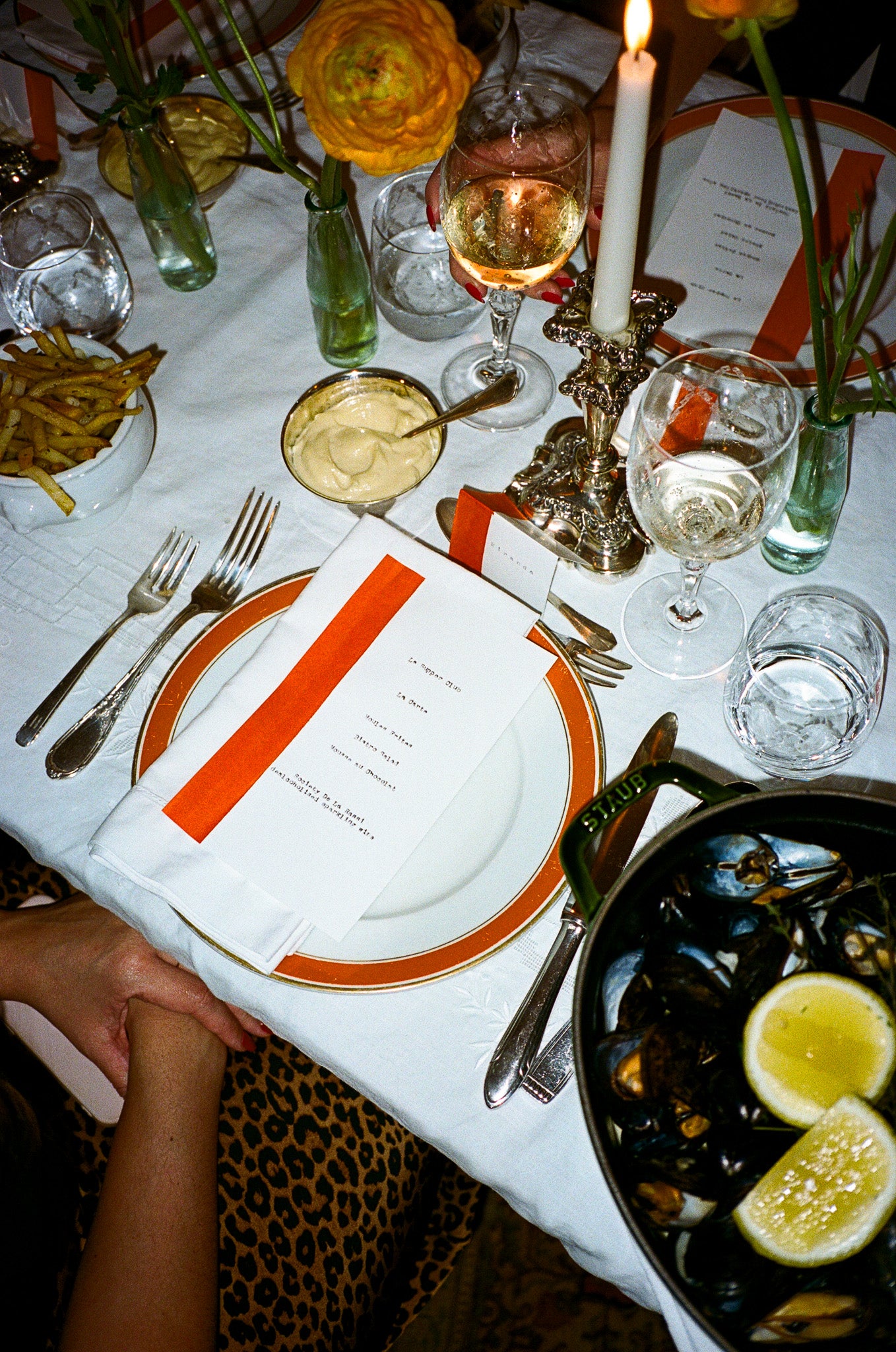 Dining table set with plates, cutlery, and a dish of mussels with lemon wedges.