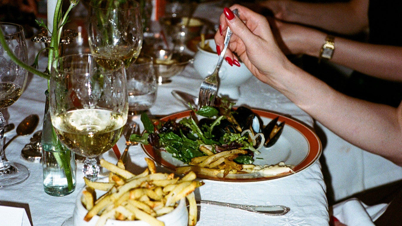 Dinner table setting with plates of food, glasses, and a candle.
