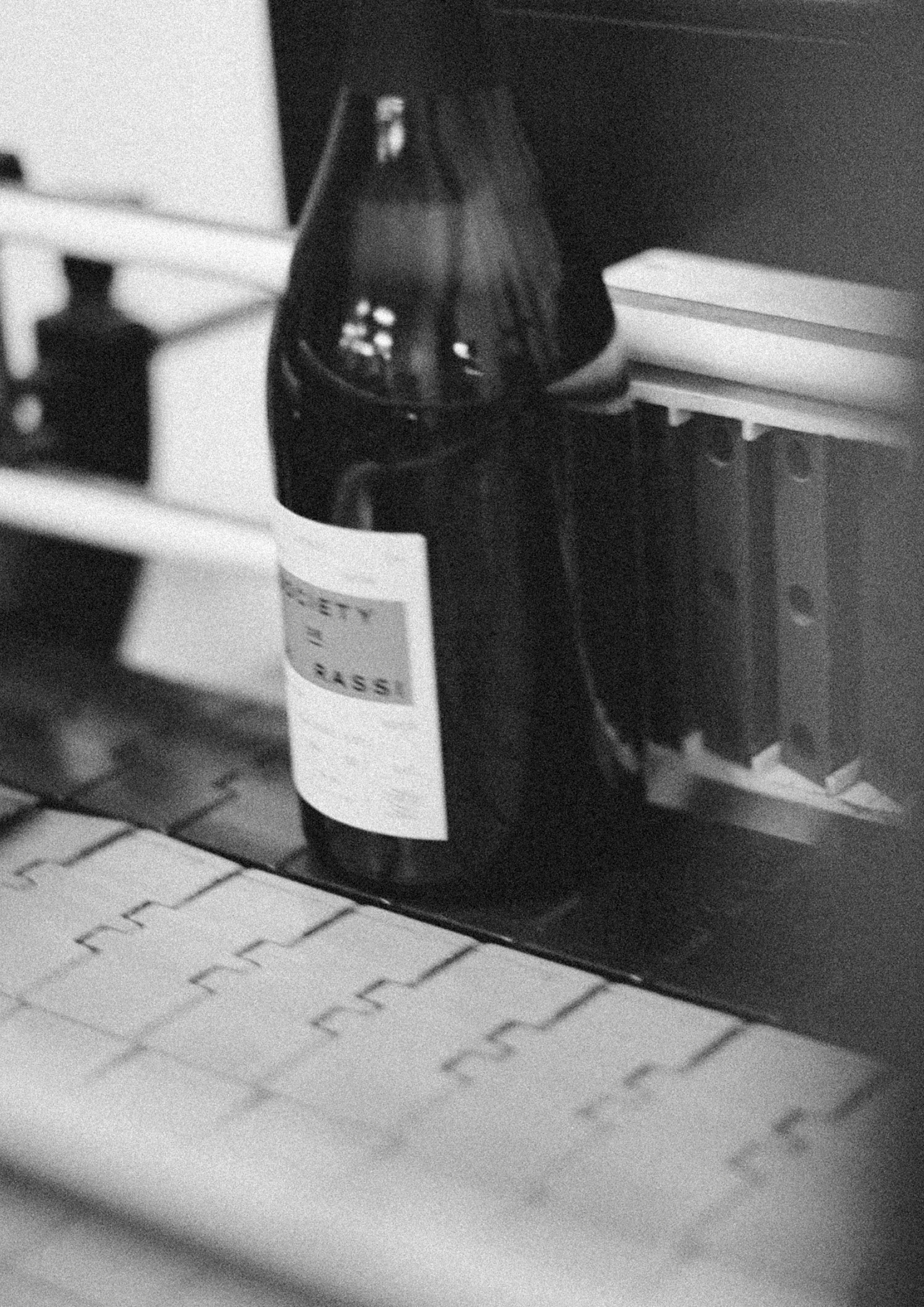 Bottle with a label on a conveyor belt in a black and white photo