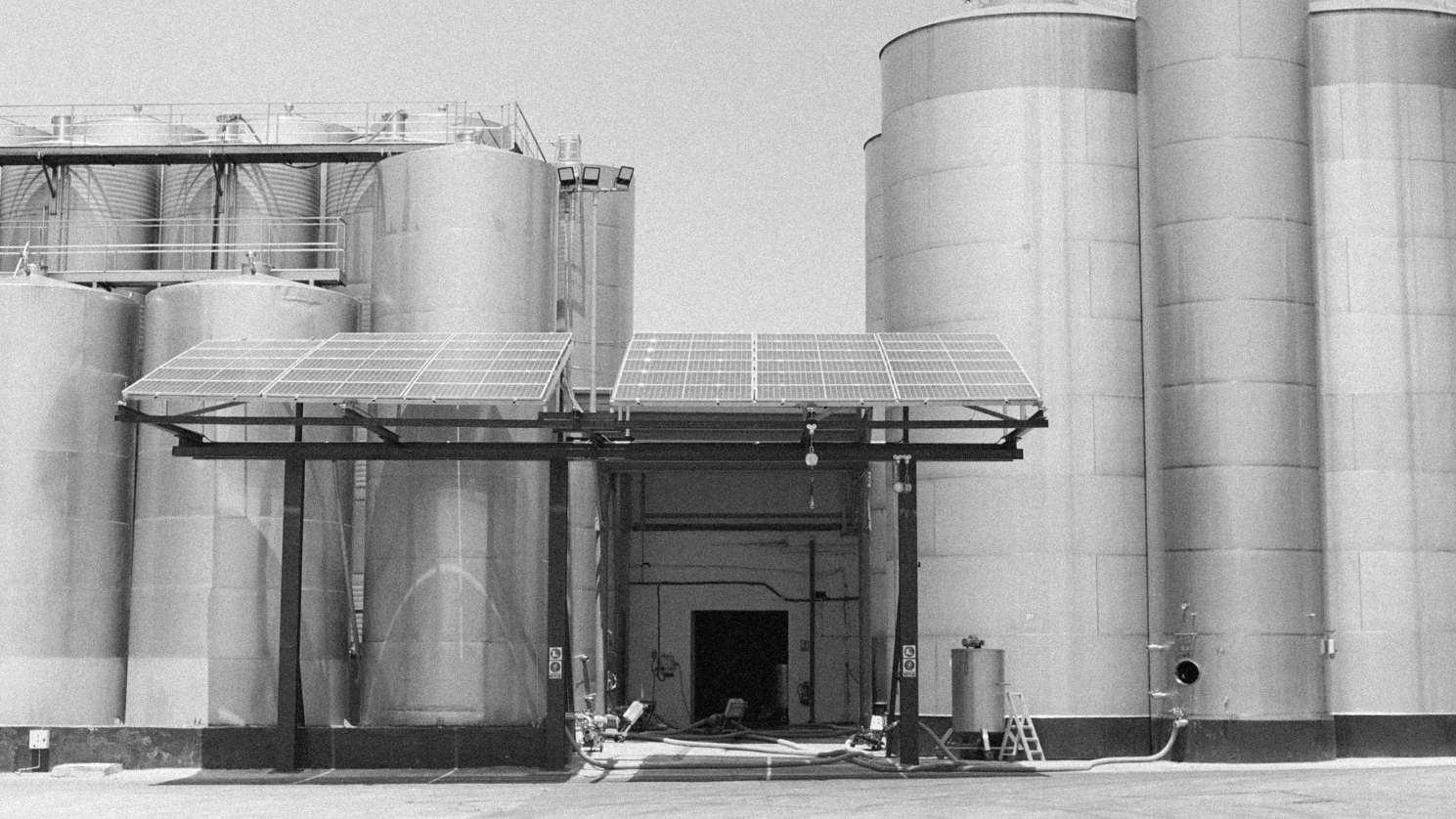 Large industrial storage tanks with a building in the center on a white background