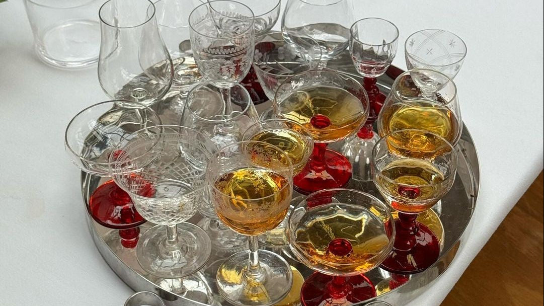 Tray of glasses with liquid and red berries on a white tablecloth.
