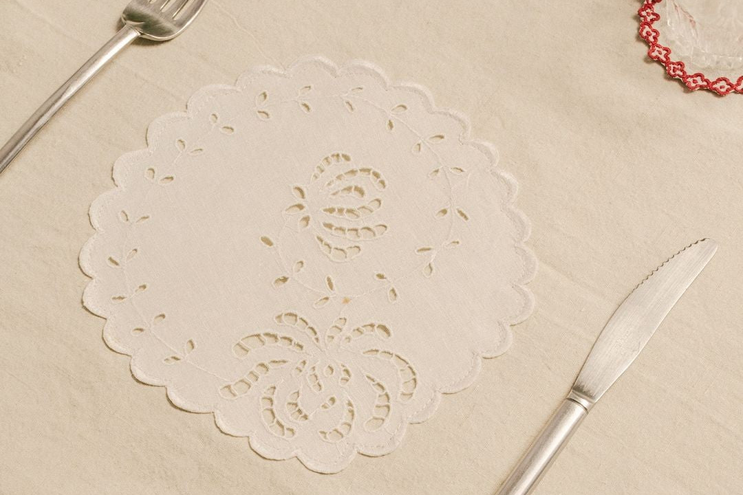 White lace doily on a beige surface with a knife and fork.