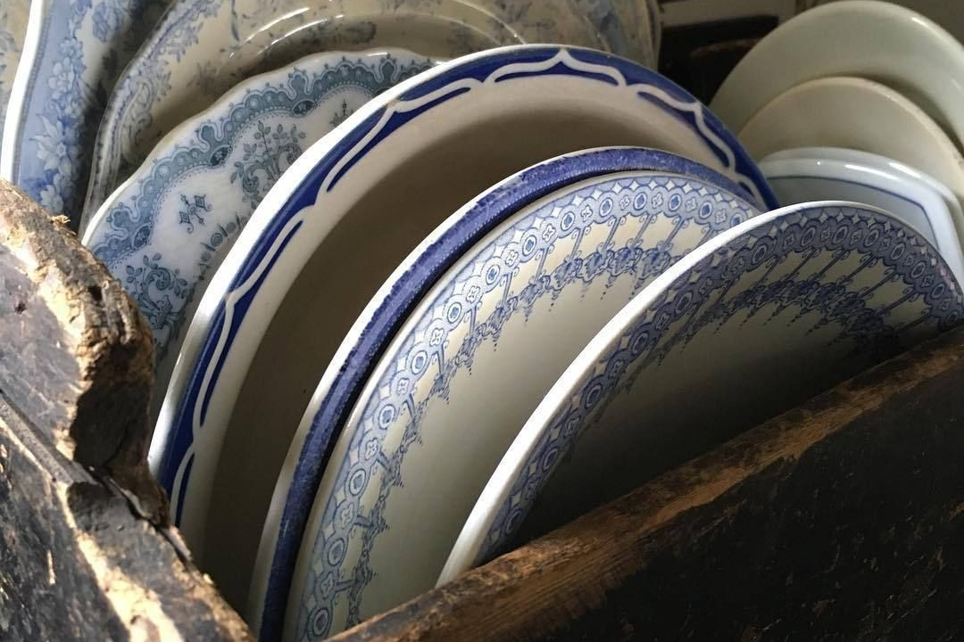 Stack of ceramic plates with blue and white patterns in a wooden box.
