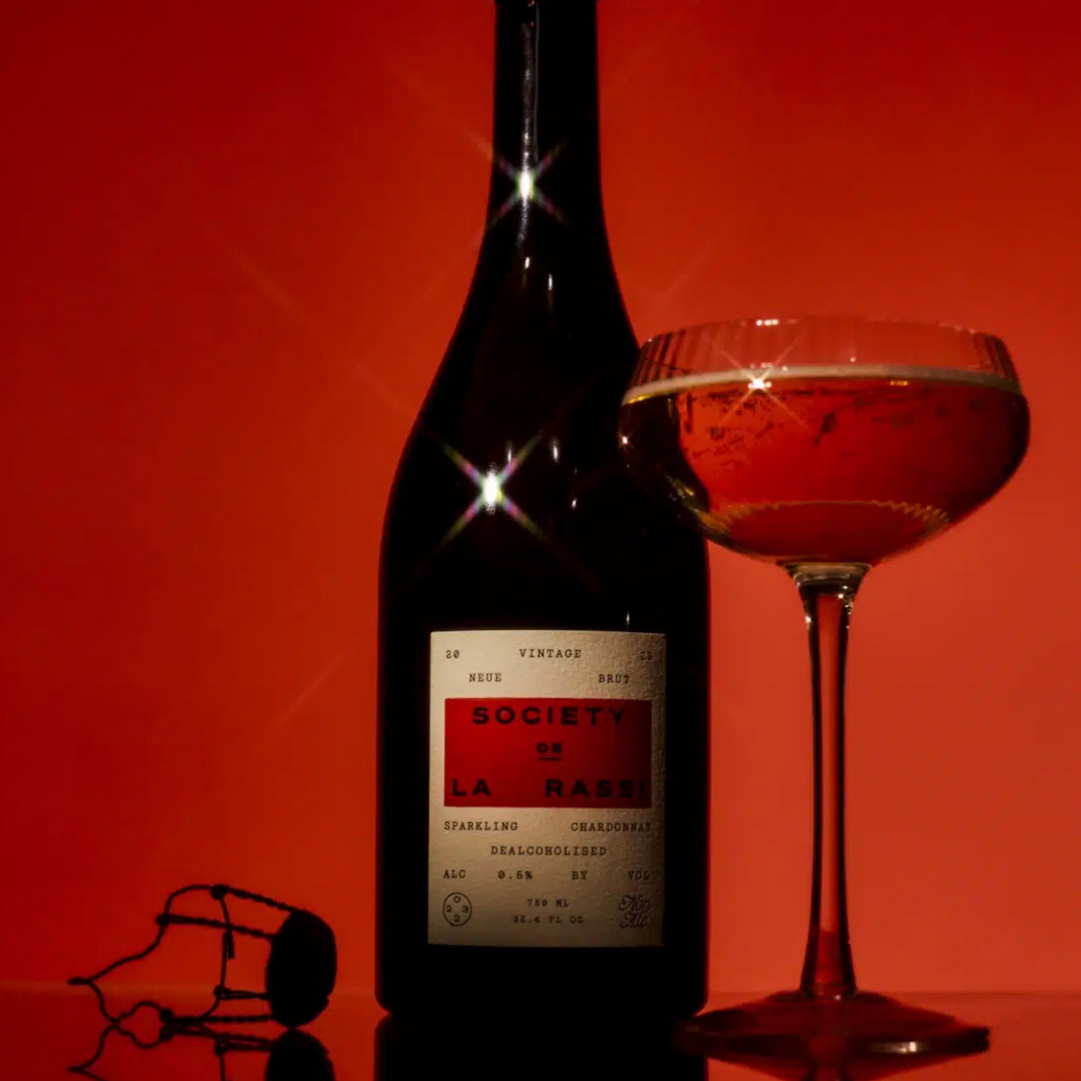 Bottle of Society de la Rassi wine with a glass on a red background