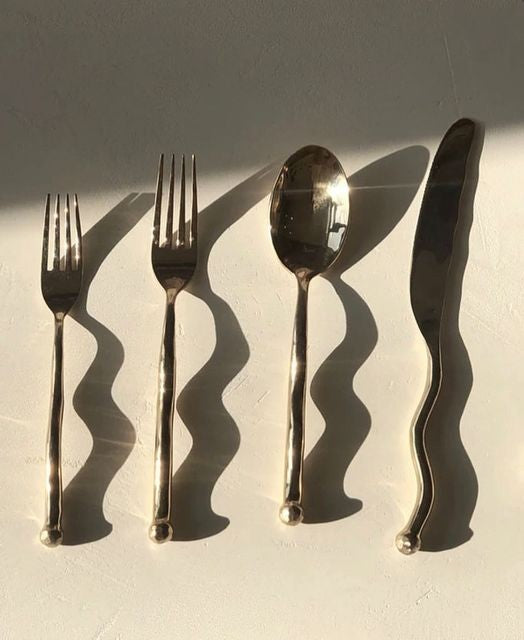 Set of silver cutlery including fork, spoon, and knife on a light background