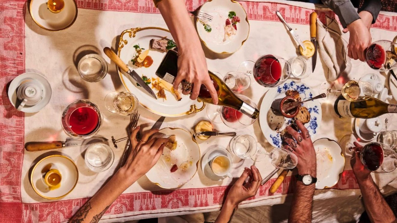 Table full of food as people hands at and drink from it