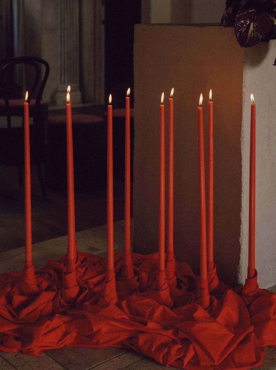 Red candles on a textured red surface with a neutral background